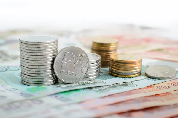 Pila de monedas rusas están en denominaciones de uno y cinco mil rublos delante de ellos una moneda con el símbolo del rublo —  Fotos de Stock