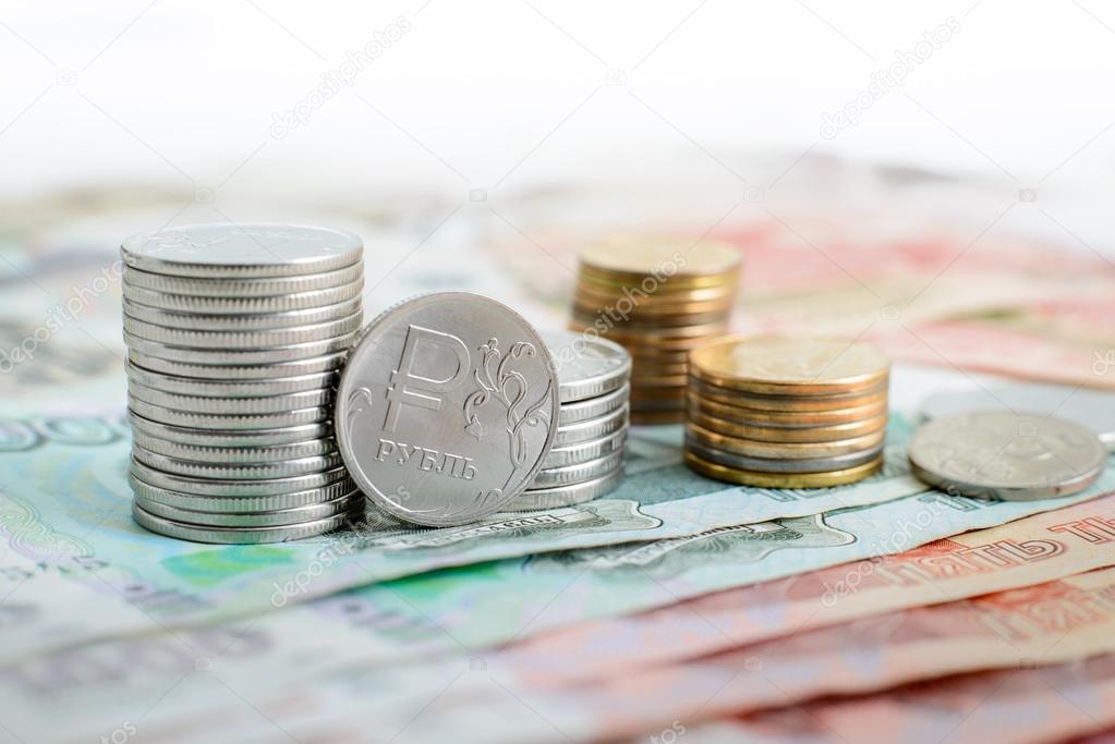 pile of Russian coins are in denominations of one and five thousand rubles in front of them a coin with the symbol of the ruble 
