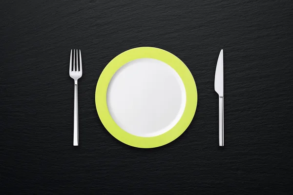 Plaat met vork en mes op grijze leisteen gestructureerde achtergrond — Stockfoto