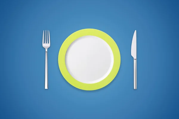 Tallrik med gaffel och kniv på marinblå bakgrund — Stockfoto