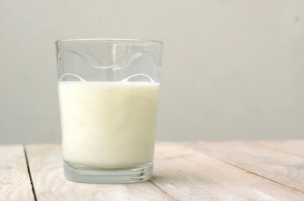 Witte melk in het glas op de houten achtergrond — Stockfoto