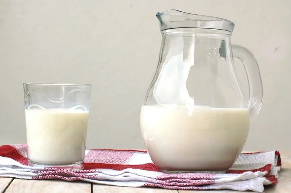 Weiße Milch im Glas mit dem Krug auf dem Holzgrund — Stockfoto