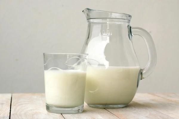 Latte bianco nel bicchiere con la brocca sullo sfondo di legno — Foto Stock