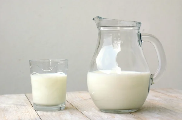 Latte bianco nel bicchiere con la brocca sullo sfondo di legno — Foto Stock