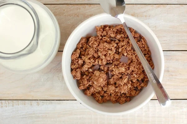 Chocolate muesli con leche en la jarra de vidrio sobre el fondo de madera —  Fotos de Stock