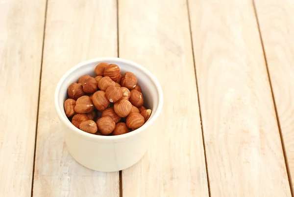 Hazelnuts in the bowl on the wooden background — Stock Photo, Image