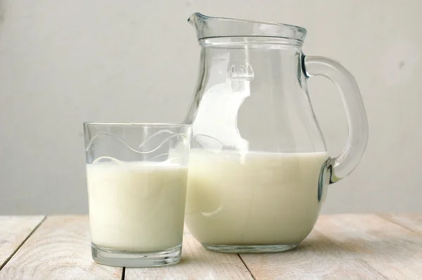 Latte bianco nel bicchiere con la brocca sullo sfondo di legno — Foto Stock