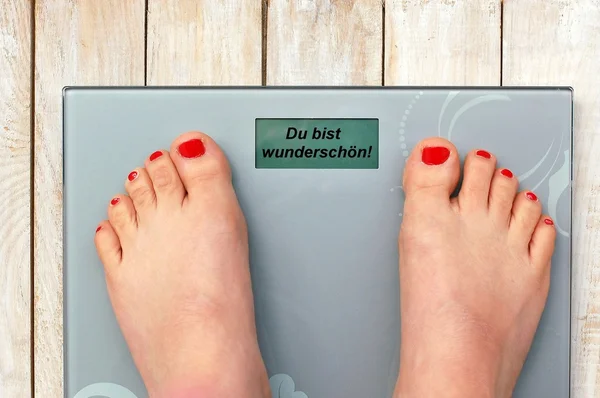Feet on scales with text you are beautiful in German language — Stock Photo, Image