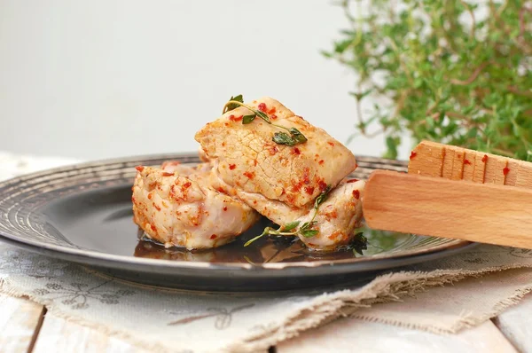 Filet de porc rôti avec piment rouge et thym frais dans une assiette foncée avec pommes de terre rôties et oignon — Photo