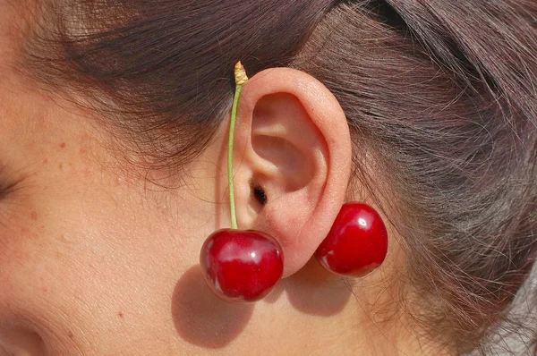 Red cherries on woman ear — Stock Photo, Image