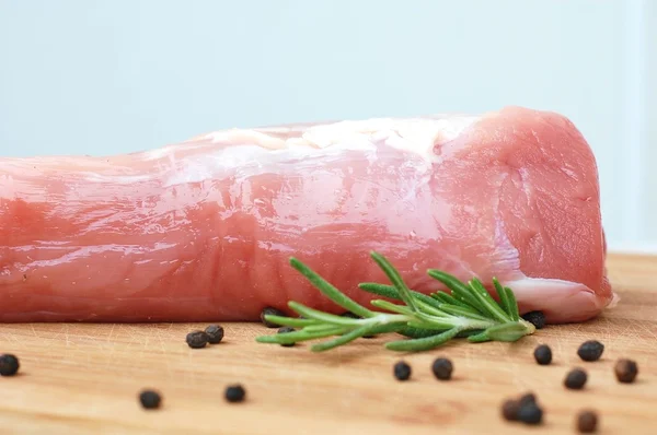 Raw pork meat tenderloin with black pepper and rosemary on wood prepared to cook Royalty Free Stock Photos