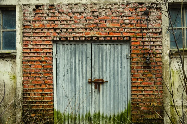 Uma velha porta de metal na parede de tijolos — Fotografia de Stock