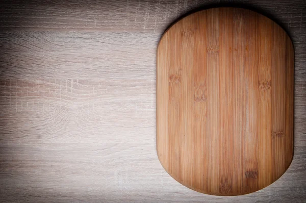 Deska do krojenia na drewnianym stołem — Zdjęcie stockowe