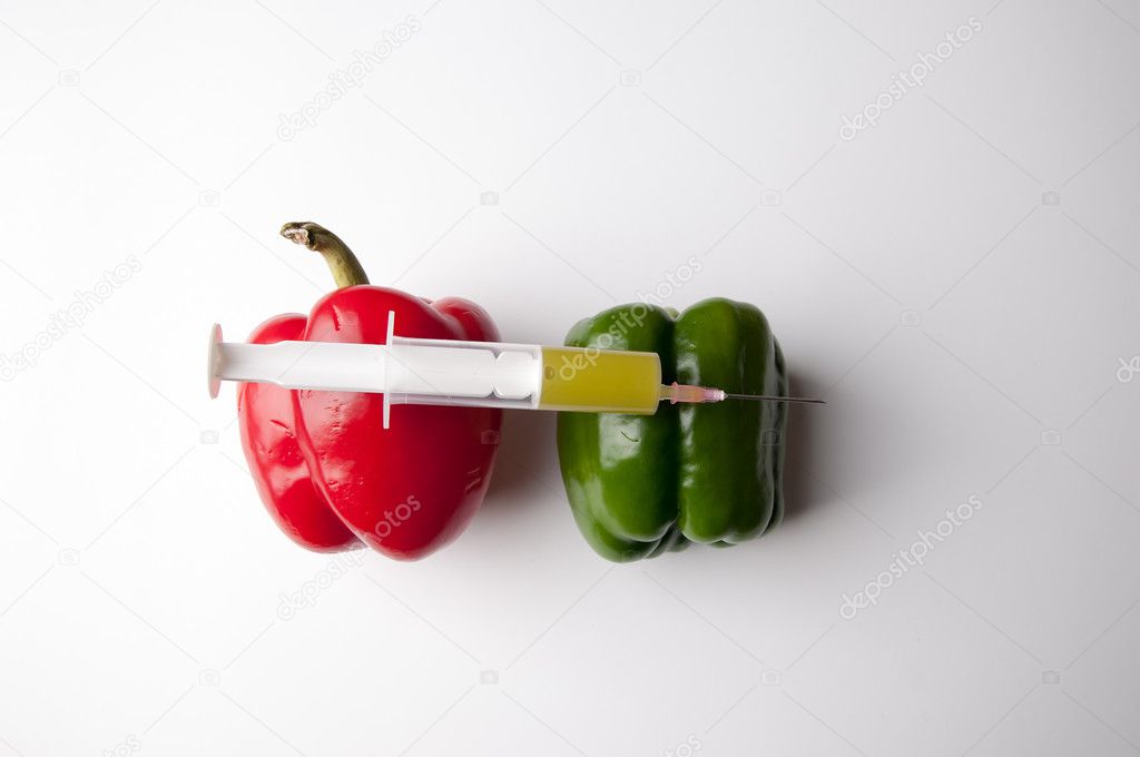 Green and reed pepper with syringe. GMO