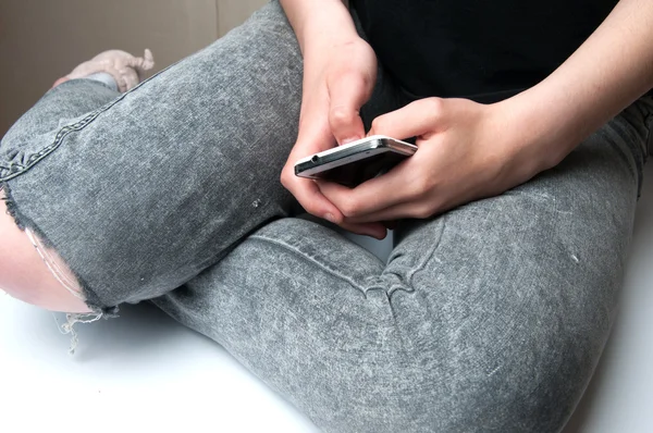 Kız beyaz bir akıllı telefon tutarak. Beyaz arka plan