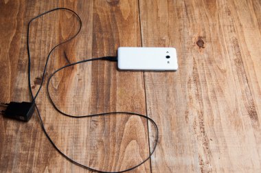 Beyaz smartphone ve adaptör şarj cihazının Üstten Görünüm