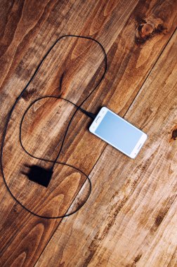 Beyaz smartphone ve adaptör şarj cihazının Üstten Görünüm