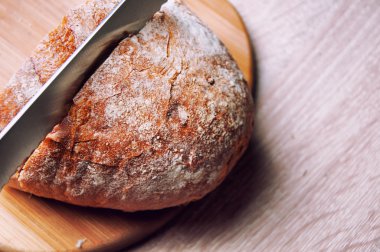 Kesme tahtası, ekmek ve tahta bir masanın üzerinde yatan bir bıçak
