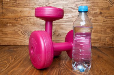 İki pembe dumbell ve su. Kadınlar için Fitness kavramı