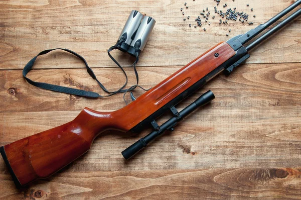 Air rifle, pellet and binoculars on a wooden background — Stock Photo, Image