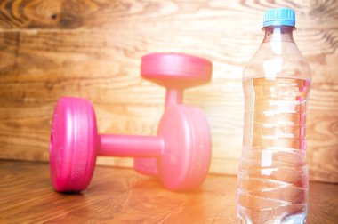 İki pembe dumbell ve su. Kadınlar için Fitness kavramı