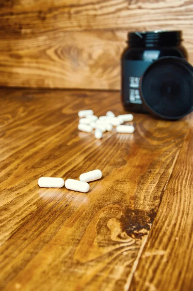 Comprimidos de creatina em uma mesa de madeira — Fotografia de Stock