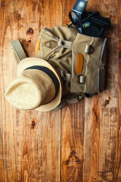 Tourismuskonzept. Rucksack, Hut und alte Kamera isoliert auf Holz — Stockfoto