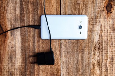 Beyaz smartphone ve adaptör şarj cihazının Üstten Görünüm