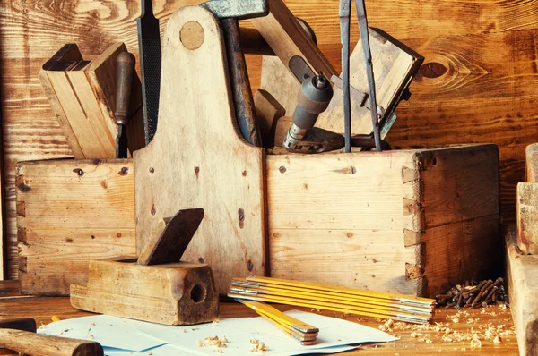 Zařízení carpenter na dřevěné desce s plány — Stock fotografie