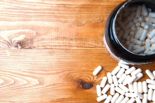 Comprimidos de creatina em uma mesa de madeira — Fotografia de Stock