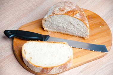 Kesme tahtası, ekmek ve tahta bir masanın üzerinde yatan bir bıçak