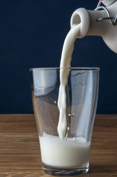 Latte versato su fondo di legno — Foto Stock