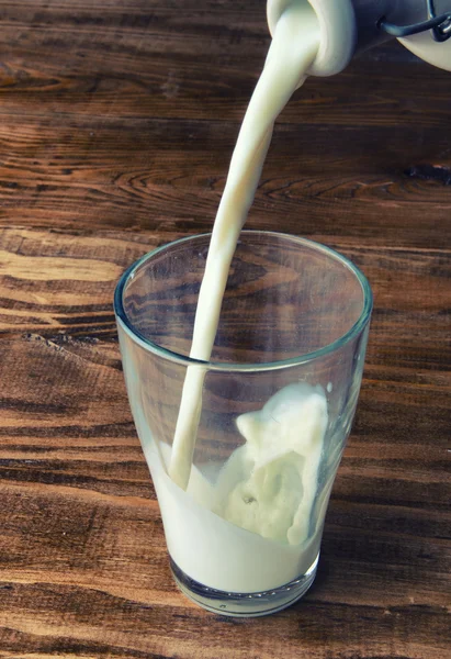 Poured milk on wooden background — Stock Photo, Image