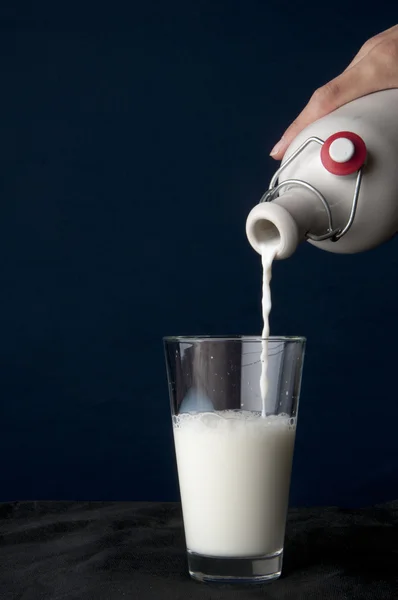 Pouring milk into a glass — Stock Photo, Image