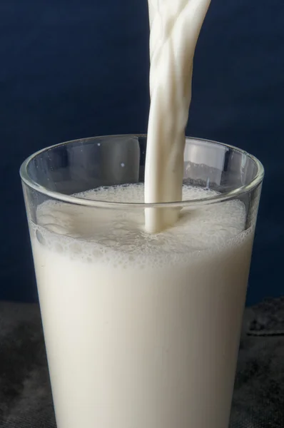 Milch in ein Glas gießen — Stockfoto