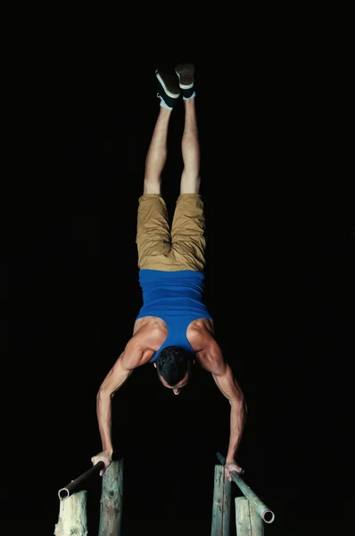 Sportieve jongeman handstanden doen. Zwarte achtergrond — Stockfoto