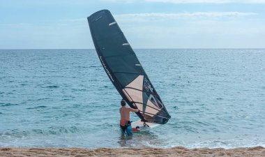 İspanya, Tenerife - 13 Mayıs 2021: rüzgar sörfü. Bir adam yelkenli bir sörf tahtasındaki yarışa hazırlanıyor. Stok Fotoğrafı
