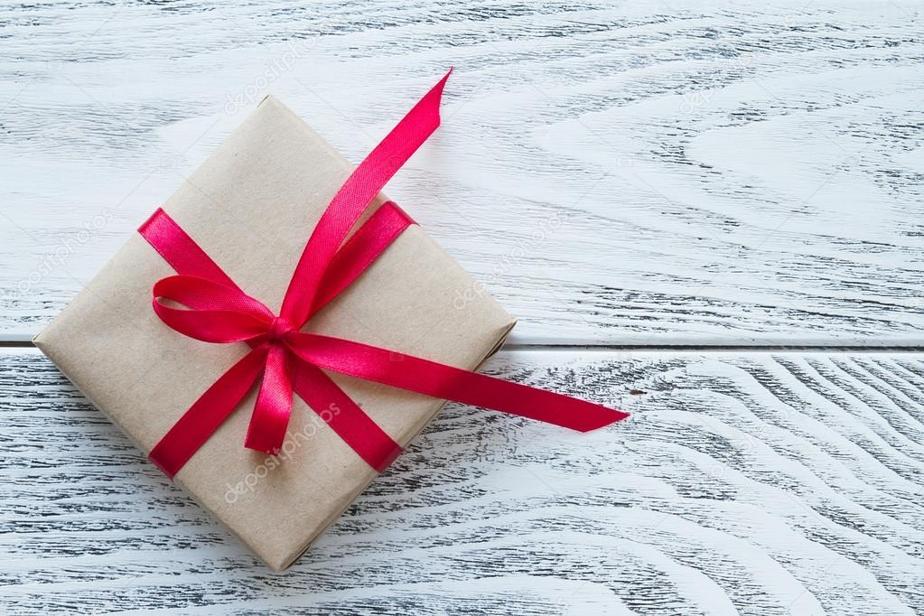 Gift box with red ribbon on the rustic background