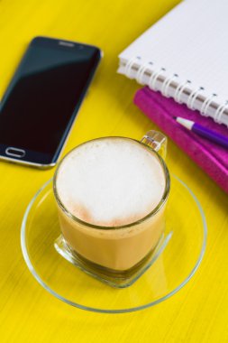 Kapuçino, not defterleri ve bir tablo bir telefonda