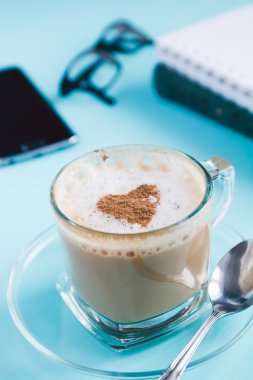 Kapuçino, not defterleri ve mavi bir tablo bir telefonda