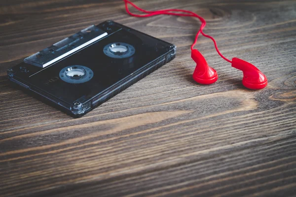 カセット テープと木製のテーブルの上のイヤホン. — ストック写真