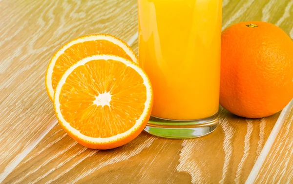 Copo de suco de laranja com laranja e metades — Fotografia de Stock