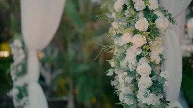 Beyaz ve yeşil çiçeklerle süslenmiş güzel bir düğün chuppah, zarif bir açık hava seremonisi..