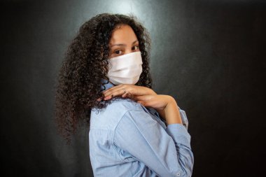 Cerrahi maskeli Afro kökenli bir kadın. Burnu ve ağzı solunum hastalıklarına karşı koruyor..