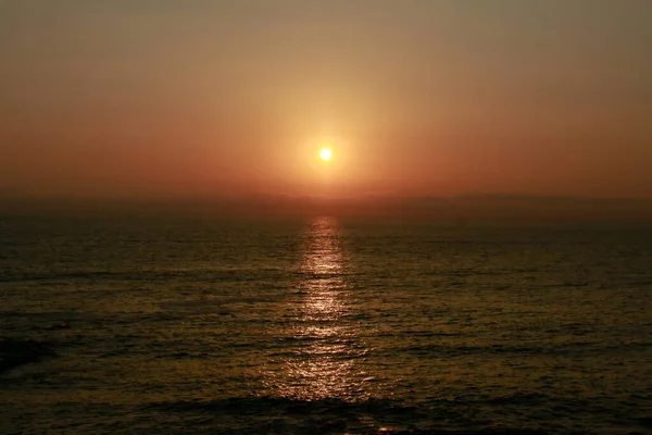 Sunset on the beach, the sun sets into the sea.