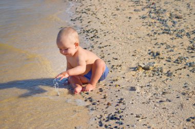 Çocuk deniz kenarında kumlarda oynuyor.