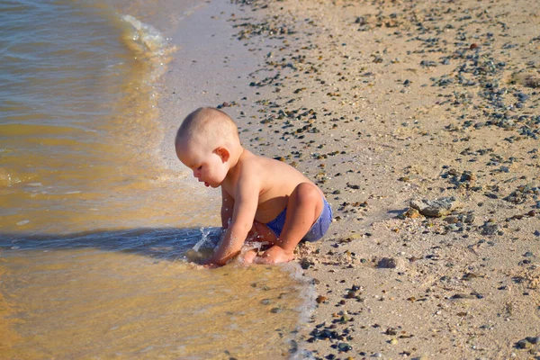 Çocuk deniz kenarında kumlarda oynuyor.