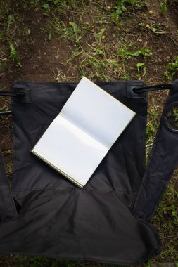 Avluda bir sandalyede açık bir kitap, hava manzaralı.