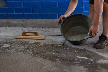 Kovayı taze beton karışımıyla dolduran bir adamın elleri.