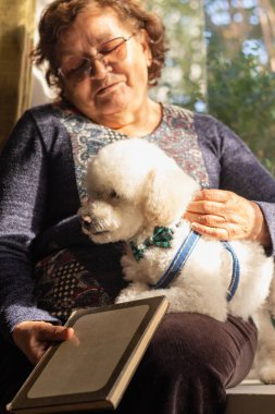 Bir büyükanne ve köpeği kitap okuyor.